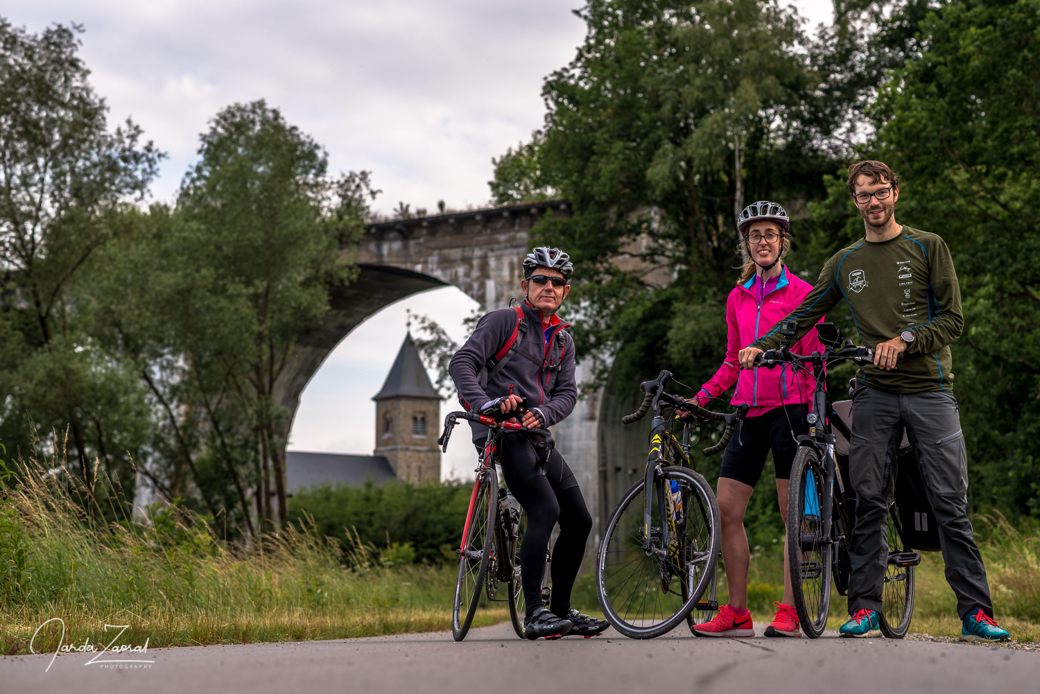 Three bikers in front of a bridge in Belgium
