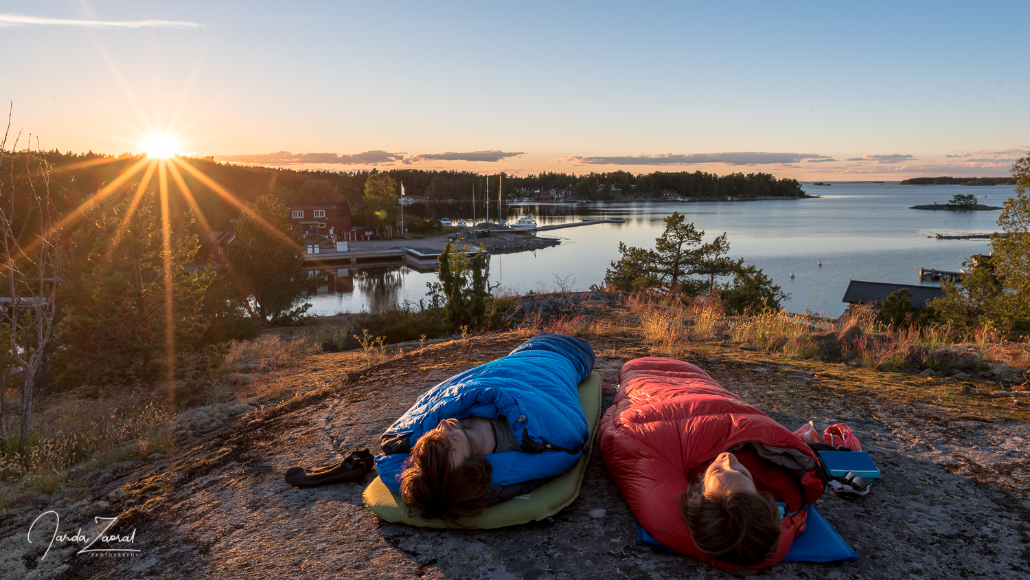 Two tourists chilling during sunrise in their sleeping bags on a Swedish island