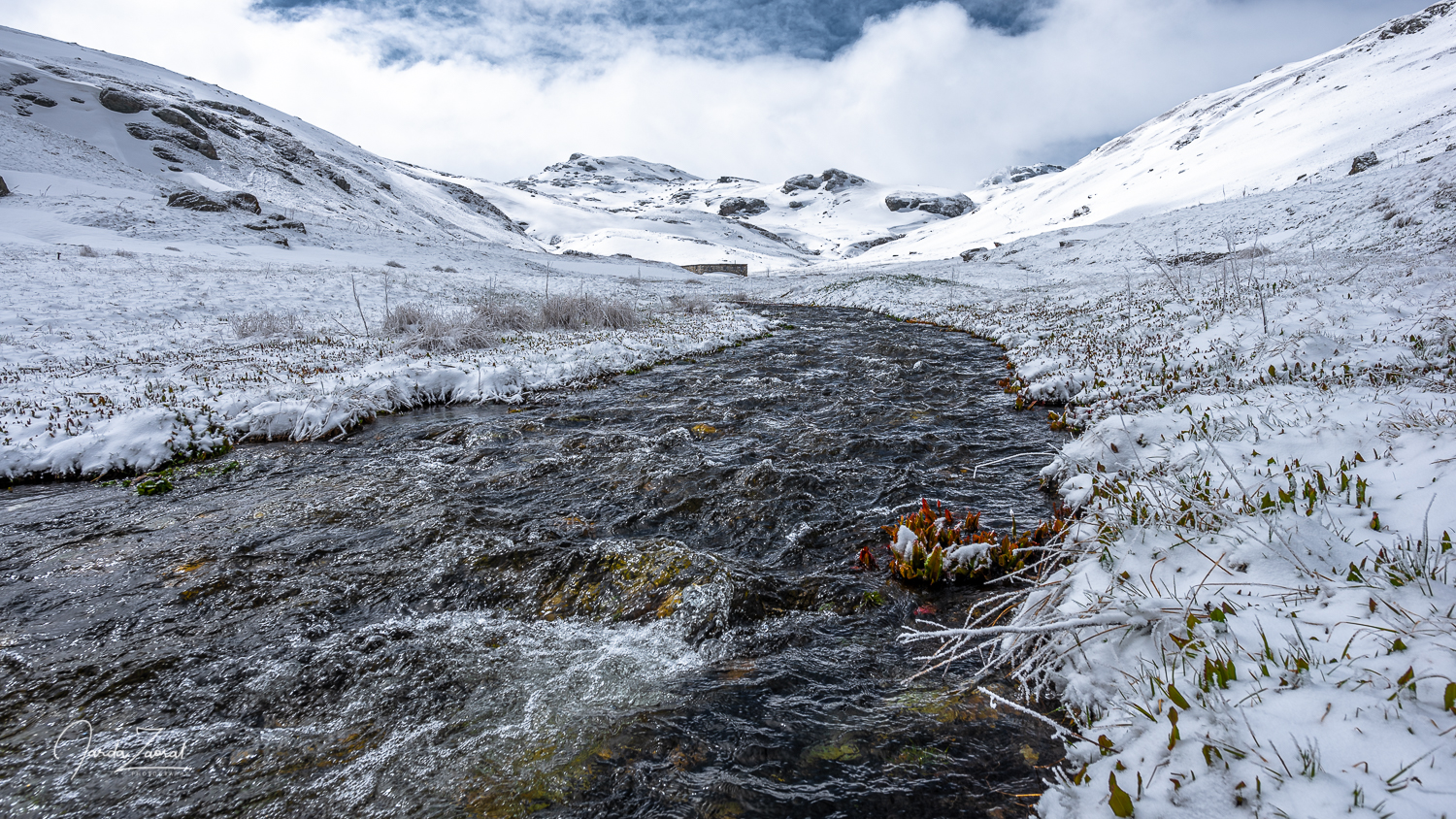 View over a river and highest point of Kosovo Rudoka e Madhe covered by snow