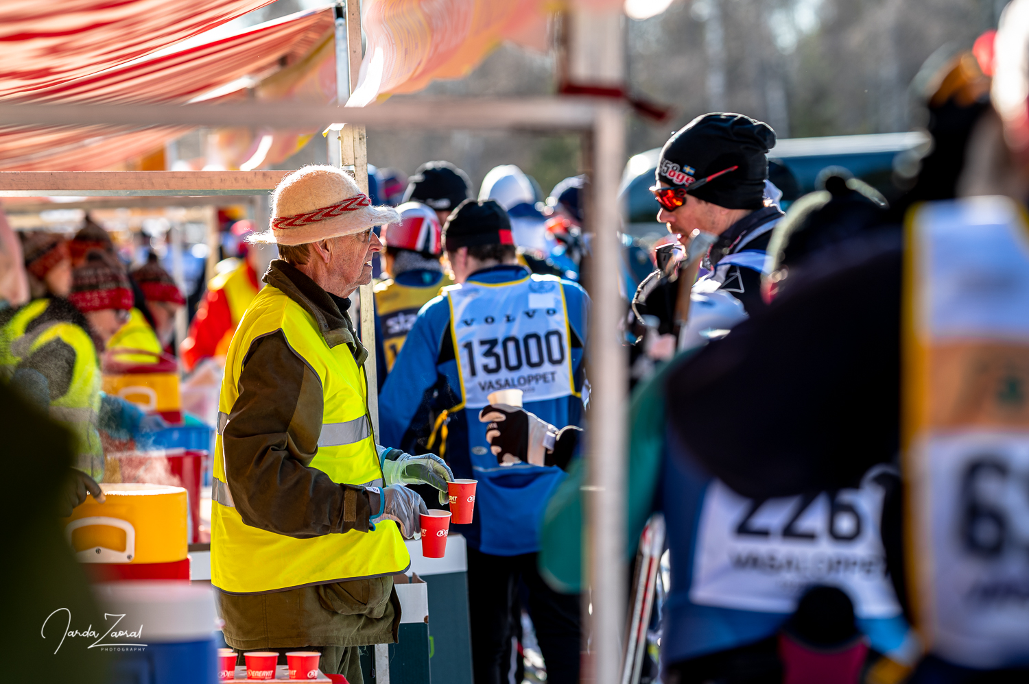 A volunteer giving out blueberry soups to a racer