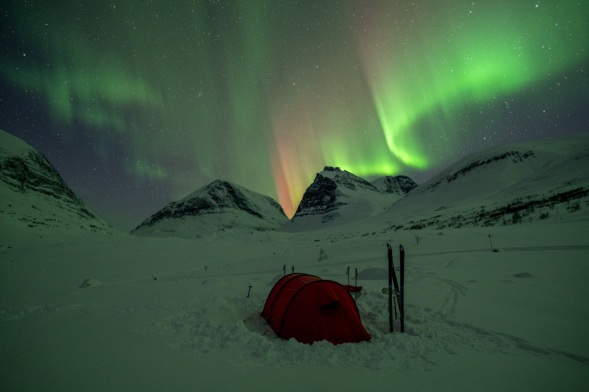 Tent in the valley under Kebnekaise and under northern lights at Kungsleden in winter